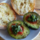 An avocado split with bruschetta, olive oil, fresh basil, salt and pepper. A toasted ciabatta roll drizzled with olive oil to accompany it